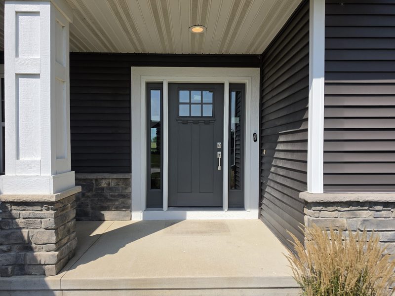 Craftsman front entry with stone columns and a concrete porch